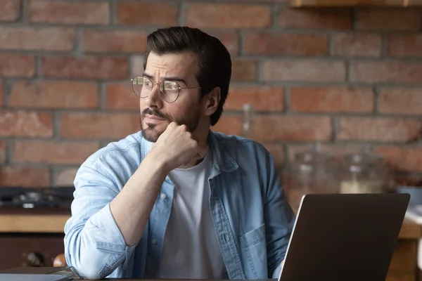 Pensive young man work on laptop thinking