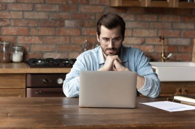 Düşünceli beyaz adam bilgisayar üzerinde çalışıyor.