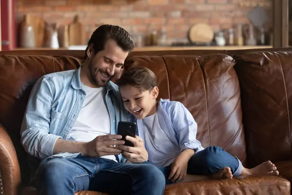 Happy little boy and dad use smartphone at home — Fotografia de Stock