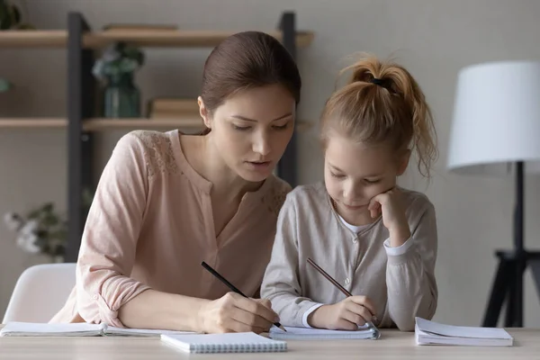 Caring mom and little daughter study together at home —  Fotos de Stock