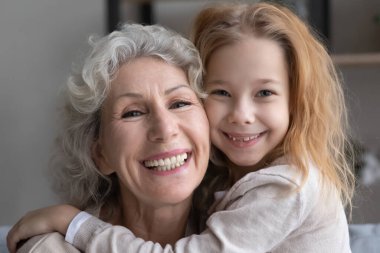 Portrait of happy old grandmother and little granddaughter hugging