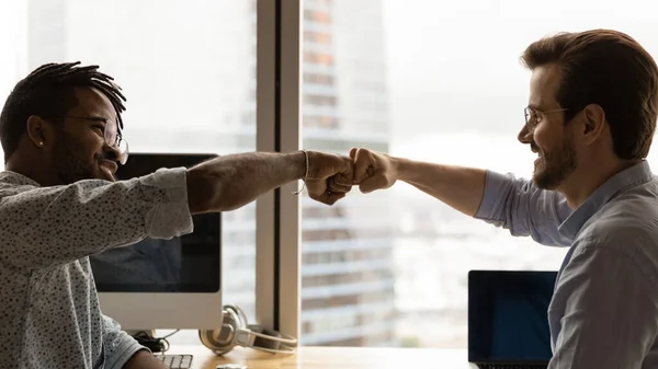 Diverse male colleagues giving fist bump at workplace