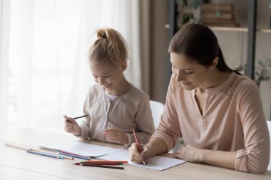 Happy mom and small daughter painting at home together