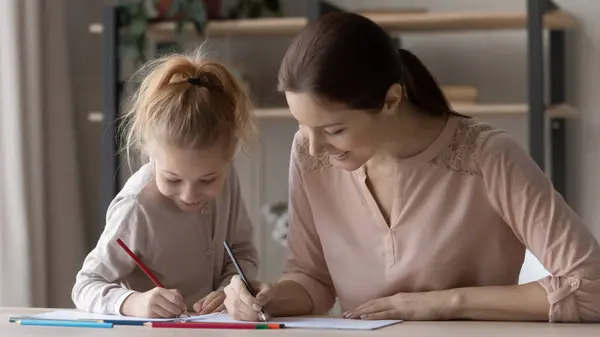 Smiling mom and small daughter drawing in album together — ストック写真