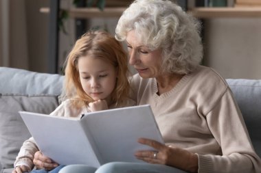 Caring senior grandmother read book with granddaughter