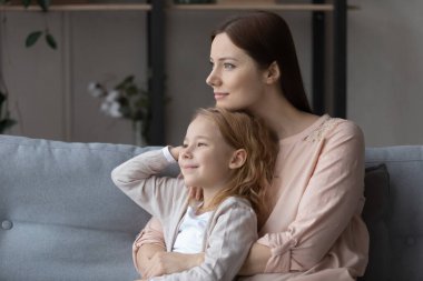 Happy young mother and teen daughter look in distance