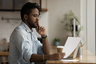 Focused African guy holding paper document learn commercial offer