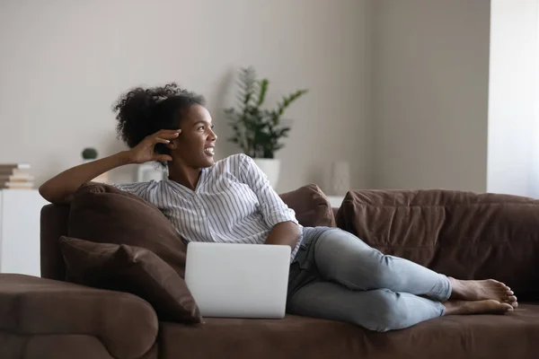 Feliz mujer afroamericana relajarse en el sofá con el ordenador portátil — Foto de Stock