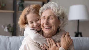 Happy senior grandmother and teen granddaughter hugging