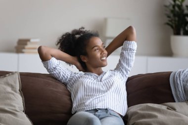 Smiling African American woman rest on couch in living room