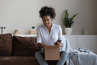Smiling biracial woman unpack box with internet delivery