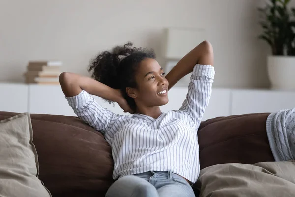 Smiling African American woman rest on couch in living room — Stockfoto