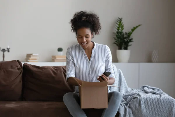 Smiling biracial woman unpack box with internet delivery — Zdjęcie stockowe