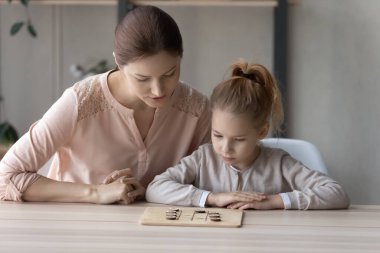 Young mother and small daughter play board game