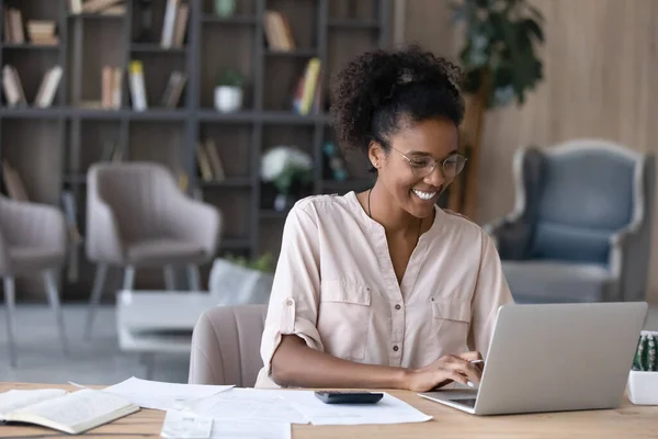 Leende afroamerikansk kvinna hantera ekonomi på laptop — Stockfoto