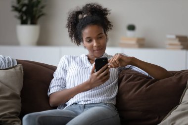 Young African American woman relax at home using cellphone