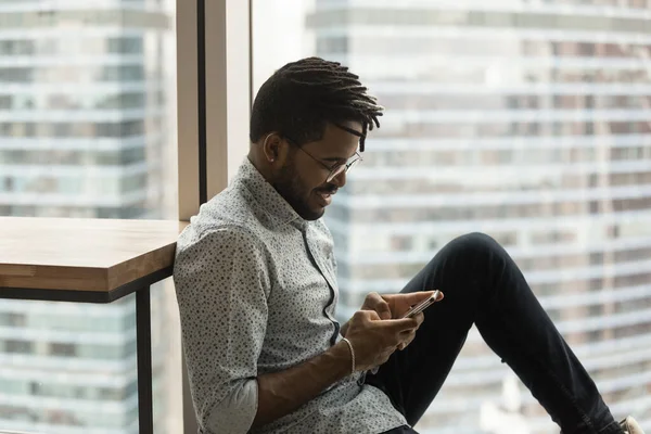 Hipster African guy sit in modern apartment with smartphone — Fotografia de Stock