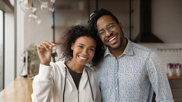 African married young couple holding keys pose on camera