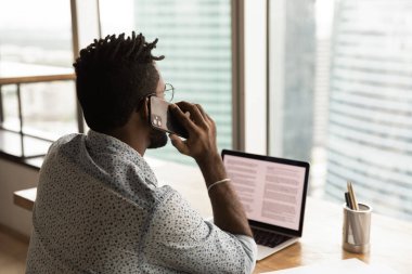 Rear view African businessman sit in office talk on phone