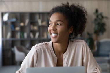 Smiling African American woman work on laptop dreaming
