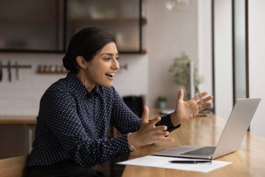 Indian woman looks at laptop feels amazed by great news