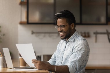 Happy African guy reading good news in letter