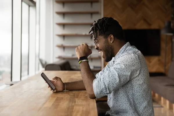 African guy looks at smartphone got great news celebrate success — Fotografia de Stock