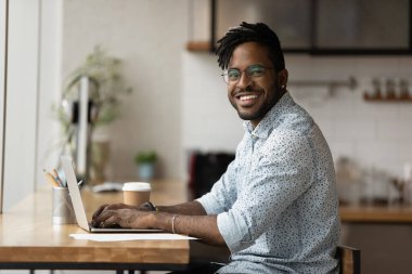 Portrait of smiling African freelancer guy working on laptop