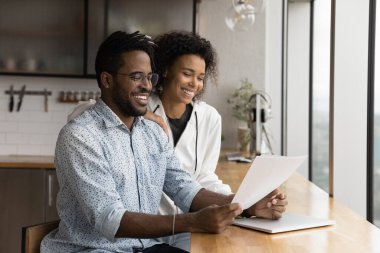 African couple holding papers reading document glad about good news