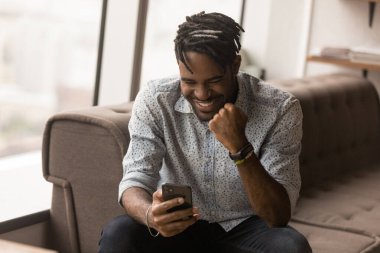 African guy read great news on smartphone feels overjoyed