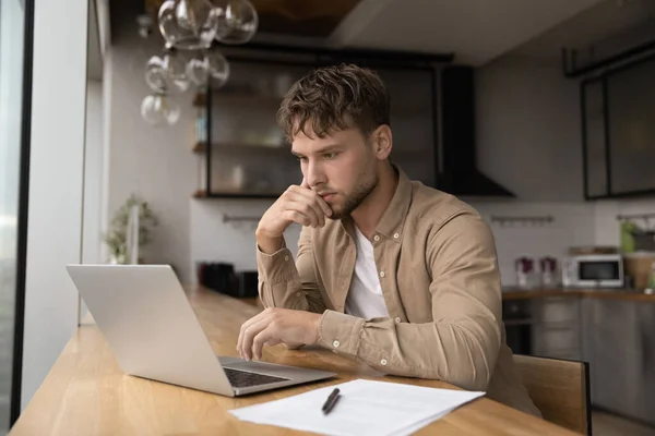Thoughtful freelancer man doing research working on laptop — Fotografia de Stock