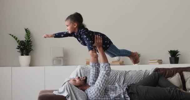 Loving young biracial dad lifting in air little cute daughter. — Vídeo de Stock