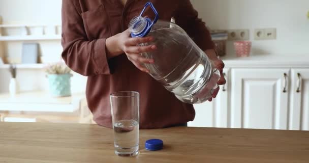 Closeup female holding plastic bottle pouring still water into glass — Stock Video