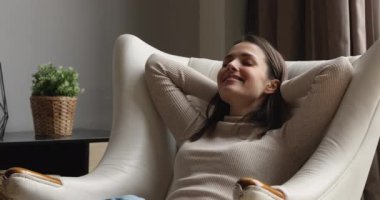 Happy peaceful young woman relaxing in comfortable armchair.
