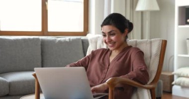 Indian woman looks at laptop feels happy celebrate good news
