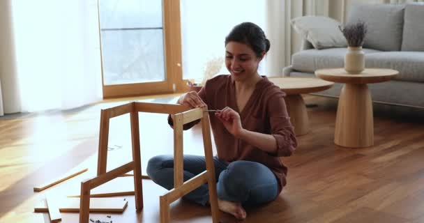 Indian woman collects wooden furniture using hand tools screwdriver — стоковое видео