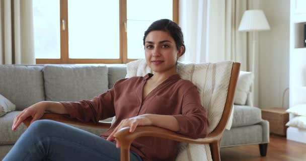 Indian woman smile look at camera relaxing on armchair indoor — Vídeos de Stock