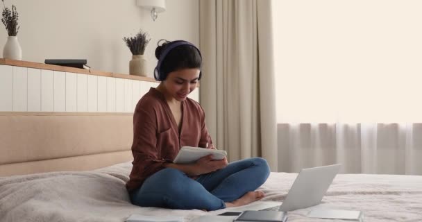 Indian student talk to online teacher e-learning seated on bed — ストック動画
