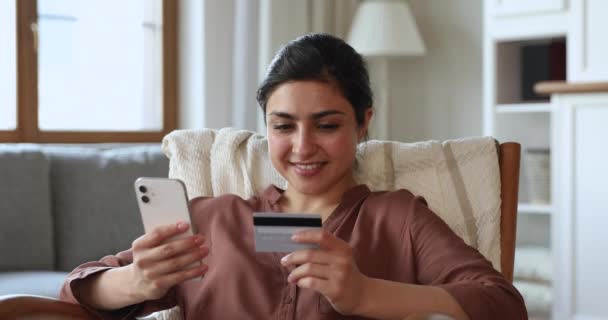 Indian woman holding card and cellphone buying goods on internet — Video