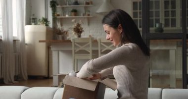 Interested young woman unboxing big carton parcel.