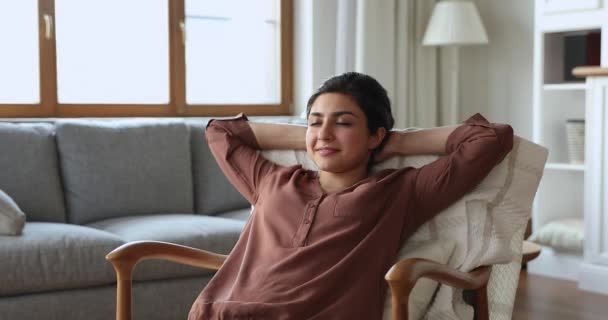 Indian woman relaxing with hands behind head on cozy armchair — Vídeo de Stock