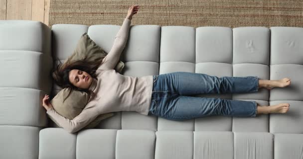 Виснажена молода жінка спить на затишному дивані . — стокове відео