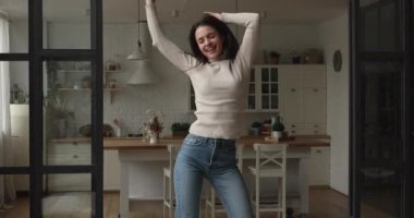 Happy young woman dancing in stylish renovated apartment.
