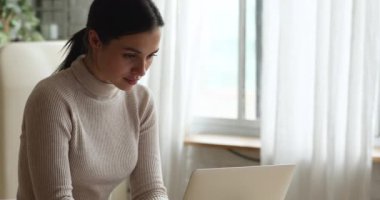 Happy young beautiful woman using computer at home.