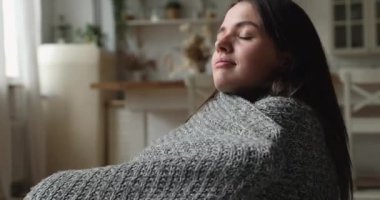 Covered in warm knitted plaid stressed woman feeling cold.