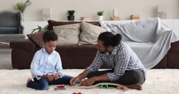 Счастливая африканская американская семья играет в игрушечную железную дорогу дома. — стоковое видео