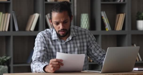 Depressed young african man reading paper notification with bad news. — Stockvideo