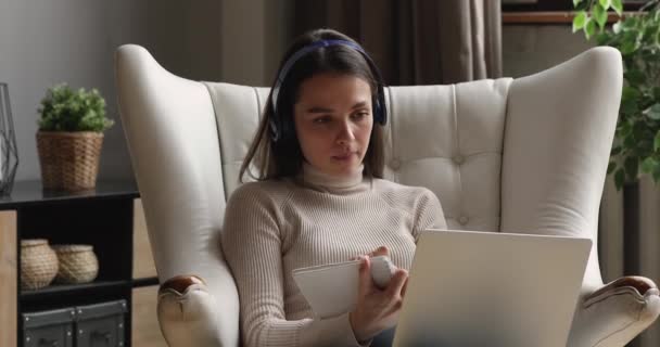 Νεαρή γυναίκα με ακουστικά ακούει εκπαιδευτική online διάλεξη. — Αρχείο Βίντεο