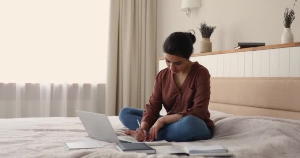 Indian woman studying using laptop, writing information taken on internet — Stock video