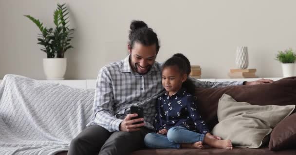 어린 아프리카 계 아버지가 작은 딸 과 핸드폰을 사용하는 모습. — 비디오